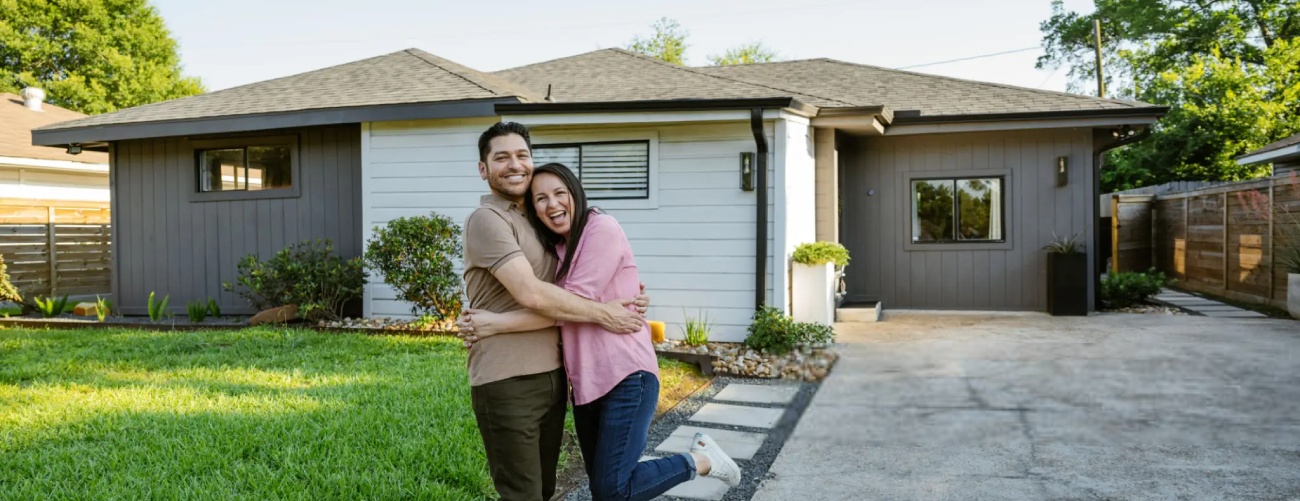 Family proudly posing in front of newly bought house