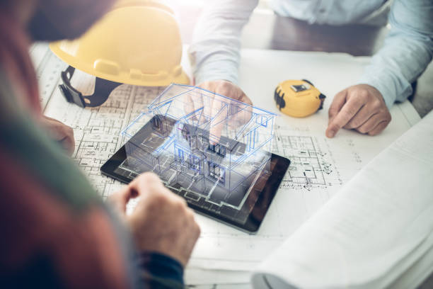 Architect and his client looking at the hologram of a house project over a tablet computer. The client is reviewing his future house layout Note to inspector: I am the author of the building project