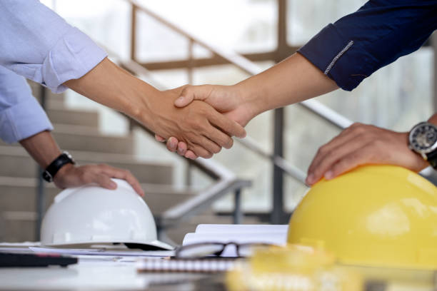 Engineers handshake on desk with helmets