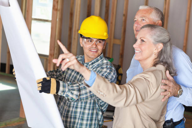 House builder discussing plans with senior adult new home owners.
