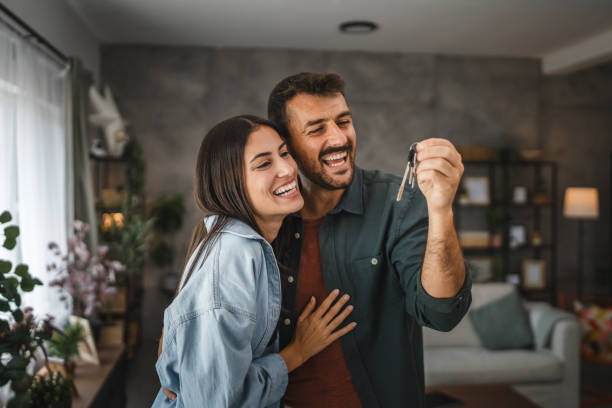 Happy couple boyfriend and girlfriend hug hold key of their new home
