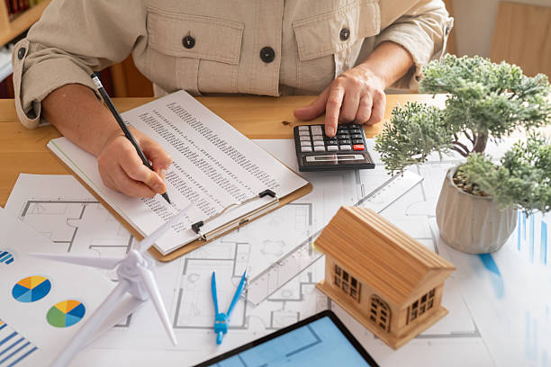 Engineer analyzing data and calculating costs for a sustainable housing project, integrating renewable energy solutions like wind turbines for ecological and economical design