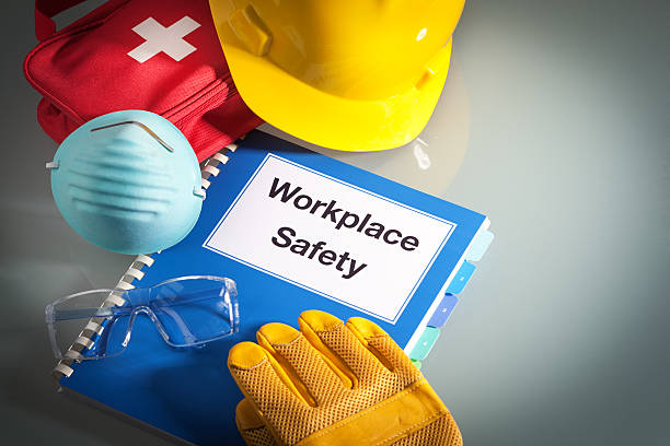 Workplace safety handbook with occupational safety equipment still life, a work training class and instruction manual for using safety equipment and administering first aid. Employment education document with protective eyewear, hard hat, first aid kit, work glove, and pollution mask. Guidance and planning tools in horizontal format with copy space.