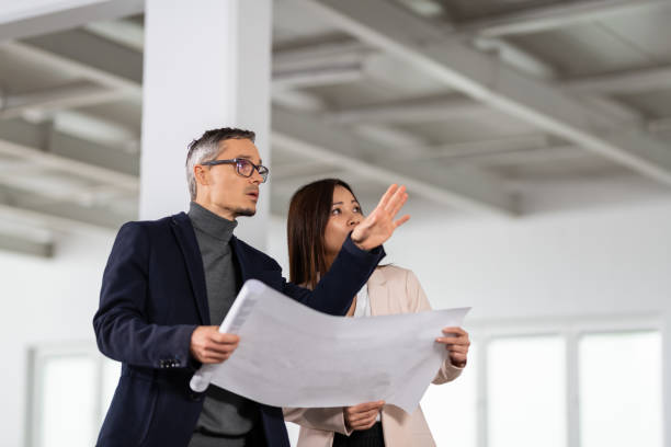 Businesspeople Meeting To Look At Plans In Empty Office