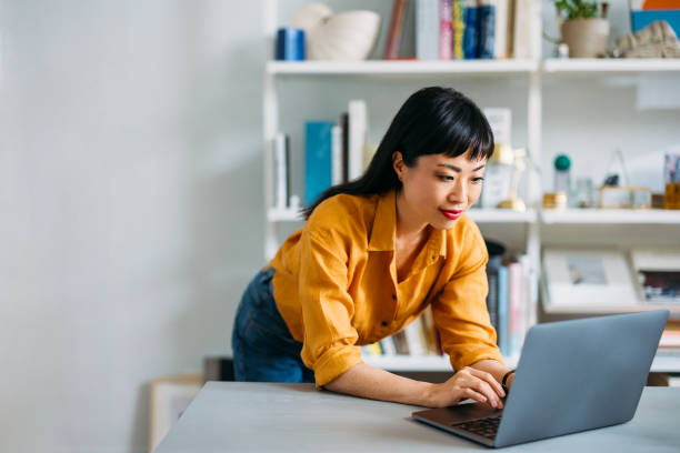 Young woman in casual attire working on a laptop in a stylish home office environment. Focused and productive atmosphere.