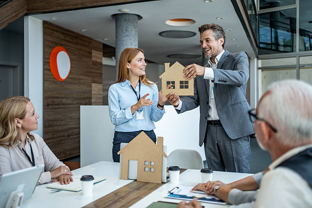 Architects presenting a new housing project using cardboard models during a meeting in a modern office, discussing and sharing ideas with their team