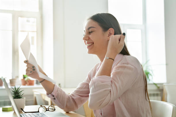 Happy female worker excited getting business letter with promotion news, satisfied woman celebrating corporate success reading report with great result or personal achievement. Rewarding concept