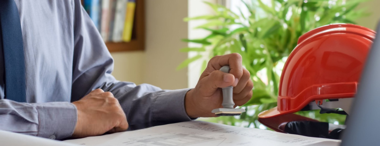grok-image-ab52af73-db30-483b-82be-a63ed86fc5e0 Architect man or male engineer hand stamping rubber stamper on blueprint paperwork at office. Authorized allowance permission approval concept.