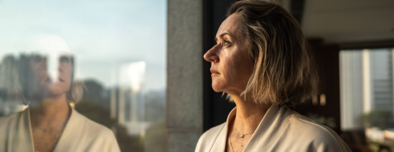 Contemplative mature woman looking through the window