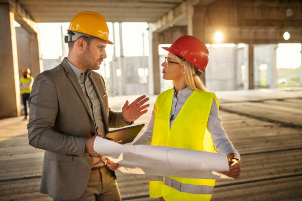 Young male and female architects looking at floor plans on a construction site