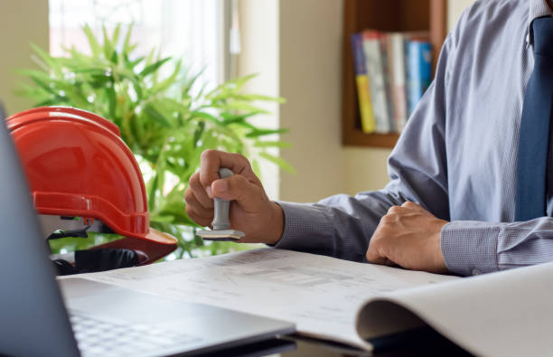 Architect man or male engineer hand stamping rubber stamper on blueprint paperwork at office. Authorized allowance permission approval concept.