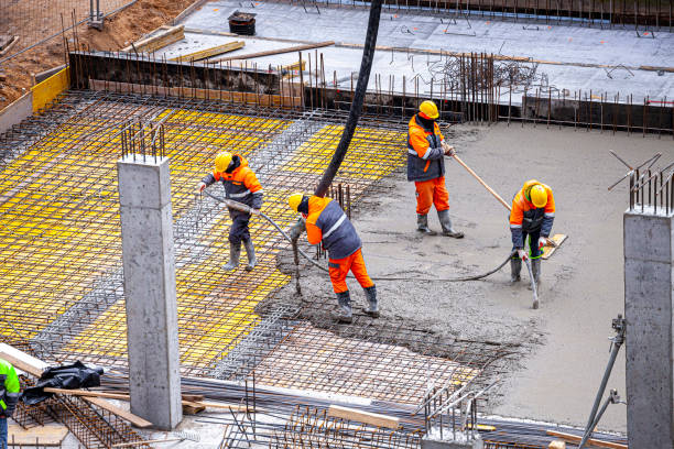 Workers pouring concrete. Concrete pouring on the construction site. Concrete pump. Reinforcement steel, reinforcing bar, rebar, foundation plate. Unrecognizable people