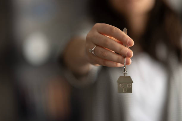 House model and key in home insurance broker agent hand or in salesman person.