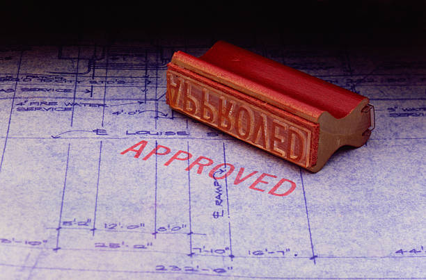 Approval stamp sitting on set of blueprints