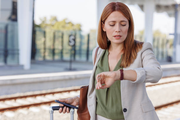Worried businesswoman checking the time on her wristwatch at the train station.