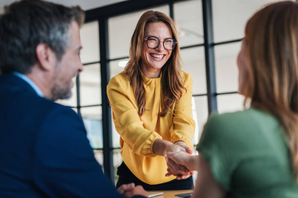Business people shaking hands in the office. Two entrepreneurs shaking hands on job interview in board room. Corporate business team discussing new agreement. Female manager discussing new project with her colleagues. Company owner on a meeting with new employee in her office.