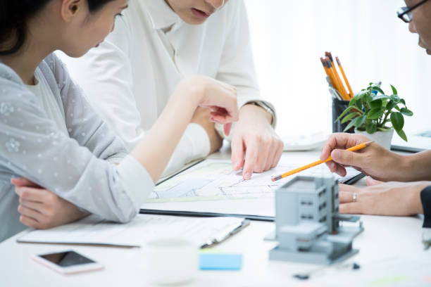A couple and employees are talking while looking at the materials in the meeting table where the model of the house is placed.