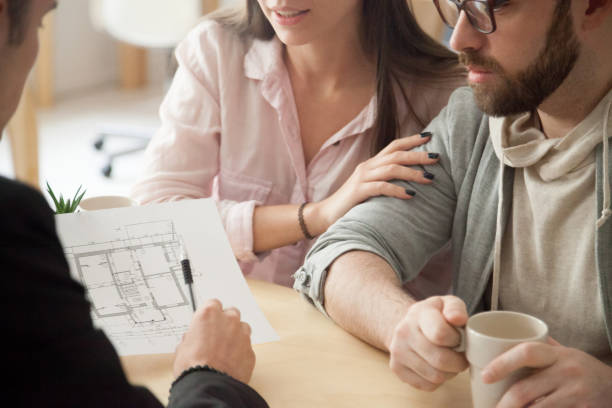 Close up of millennial couple visiting architect or designer office, consulting about future house project, young spouses deciding to buy first apartment or flat together or planning home renovation.