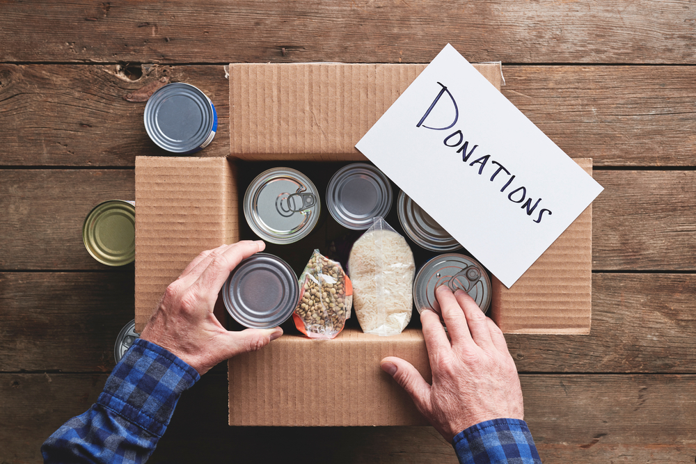 a person packing a donation box with food items