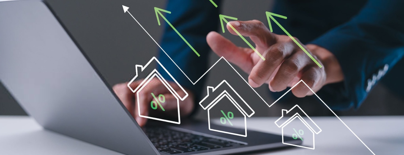 A business professional analyzes real estate data on a laptop, with graphics showing upward trends in property values.