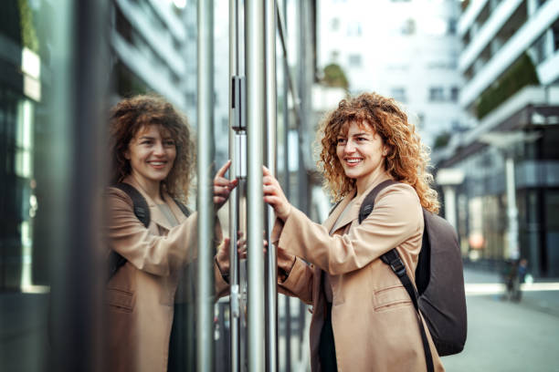 Side view of beautiful young businesswoman entering PIN code in front of company doors