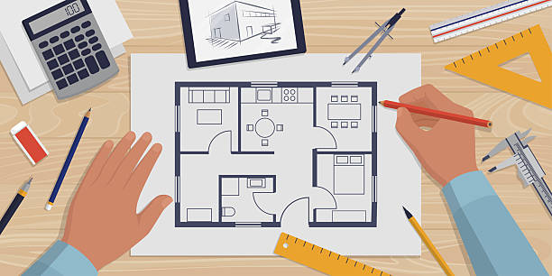 Creative architect working on a house project and checking the floor plan, desk with tools and supplies, top view