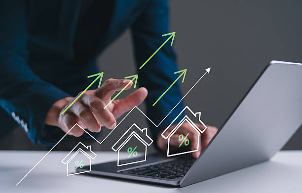 A business professional analyzes real estate data on a laptop, with graphics showing upward trends in property values.
