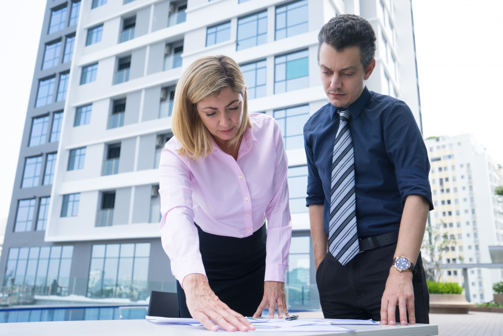 Concentrated thoughtful business colleagues standing near table and analyzing documents
