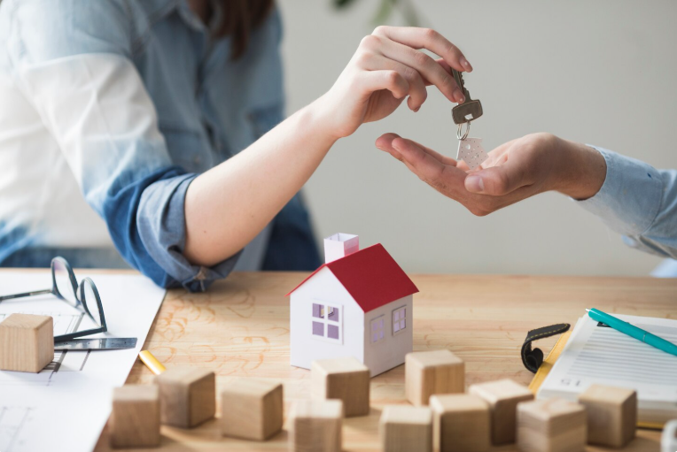 Close-up of woman's hand giving house key to man over wooden table