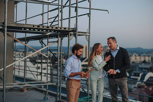 Architect taking notes while showing rooftop to an excited couple during construction of their new home