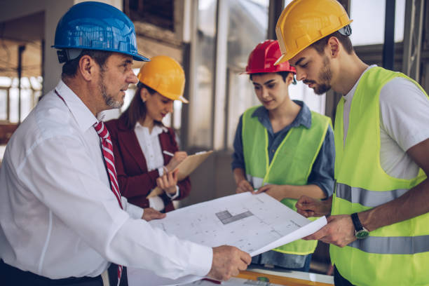 Group of architects working together on construction site, looking at the project plan.