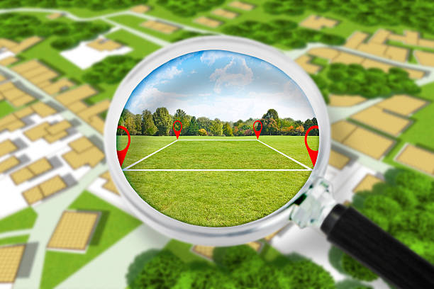 Land management with an imaginary cadastral map of territory with a vacant land available for sale or building construction - Concept seen through a magnifying glass