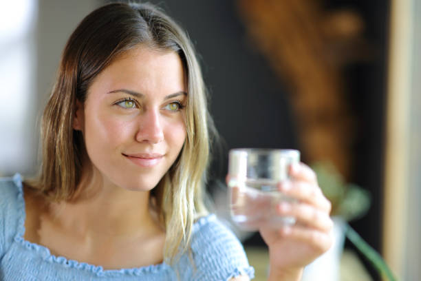 Happy teen holding water glass looking away