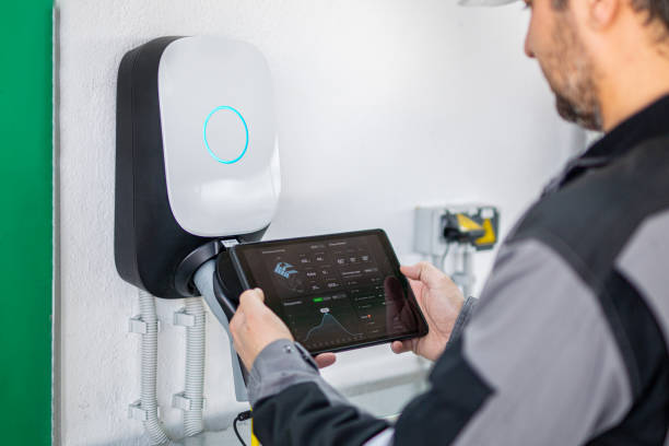 Engineer using a digital tablet to examine electric car charging station