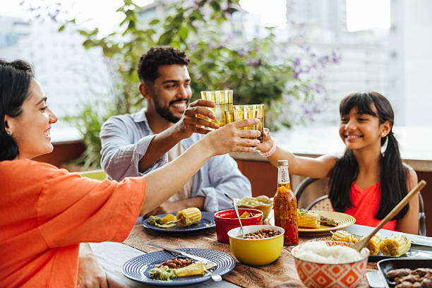 A joyful family shares a toast on a terrace, enjoying quality time and local food. The scene depicts happiness, togetherness, and a warm atmosphere during their outdoor dining experience.