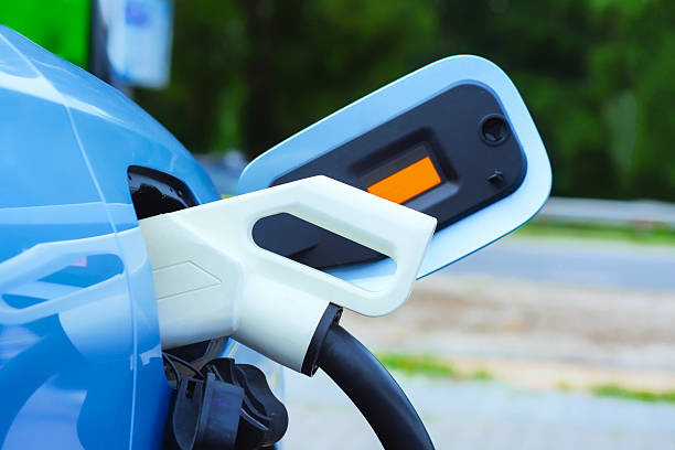 Close-up of an electric charger connected to a blue electric vehicle. Clean energy concept and the transition to green transportation