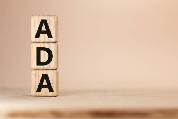 Word ADA on wooden blocks beige background top view