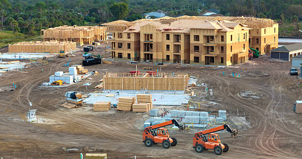 Development of residential housing in American suburbs. Unfinished frames of apartment condos with wooden roof beams under construction. Real estate market in the USA.