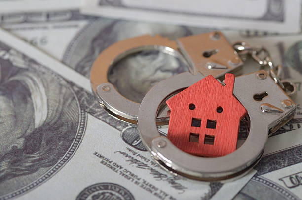 Homeownership Risk: Symbolic Arrest of House with Handcuffs and Cash