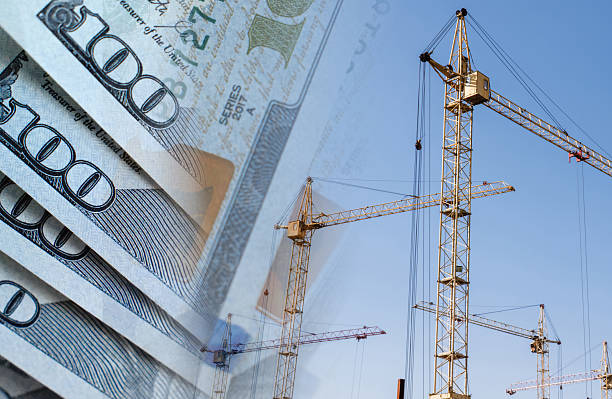 Construction cranes on a background of money. Сoncept of rising and changing construction costs