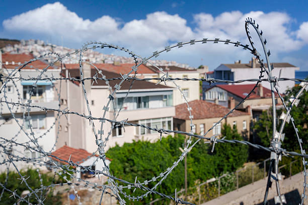 Barbed wire fence is protecting residential houses in a city under blue sky
