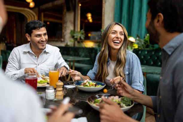 Happy group of Latin American friends having lunch together at a restaurant and laughing - food and drink establishment concepts