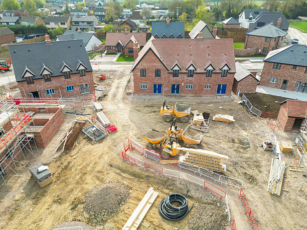Aerial view of terraced affordable homes seen nearly completed on a British construction site in rural Essex. Seen near expensive, detached executive homes.