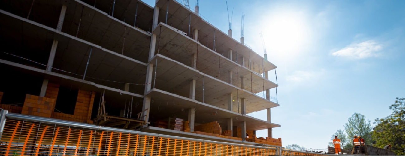 grok-image-ab52af73-db30-483b-82be-a63ed86fc5e0 Confined space with orange, plastic, safety mesh is placed around the new unfinished multi-storey building, residential complex under construction.